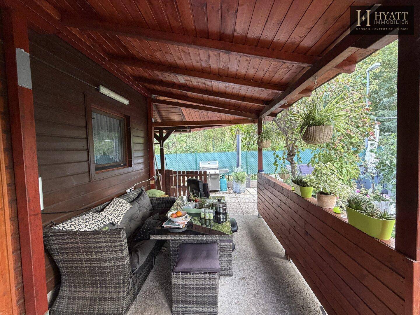 Überdachte Terrasse mit bequemen Gartenmöbeln, ideal für entspannte Stunden im Freien.