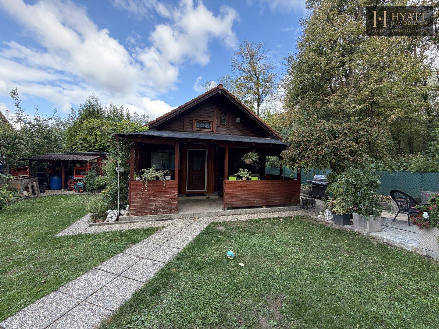 Charmantes Holzhaus mit gepflegtem Garten und einem Steinweg unter blauem Himmel.
