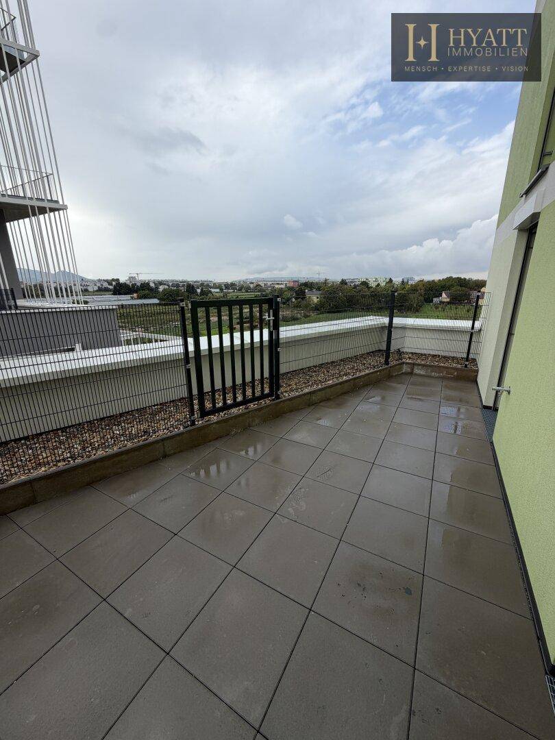 Geräumige, geflieste Terrasse mit Blick ins Grüne, bereit zur individuellen Gestaltung.
