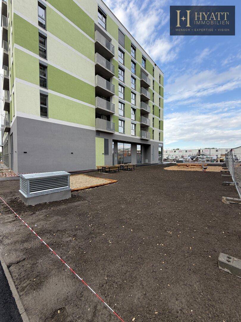 Moderne Wohnanlage mit farbiger Fassade neben einer noch unfertigen Außenfläche.