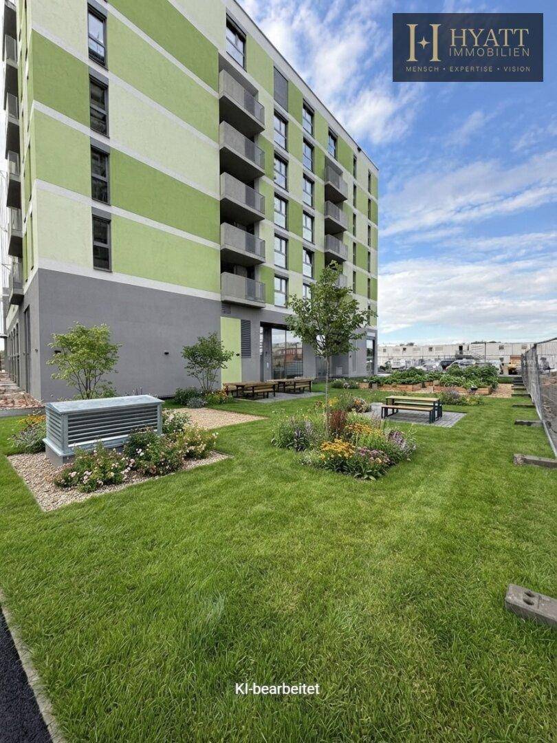 Moderne Wohnanlage mit farbiger Fassade und gepflegter Grünfläche mit Sitzbänken.