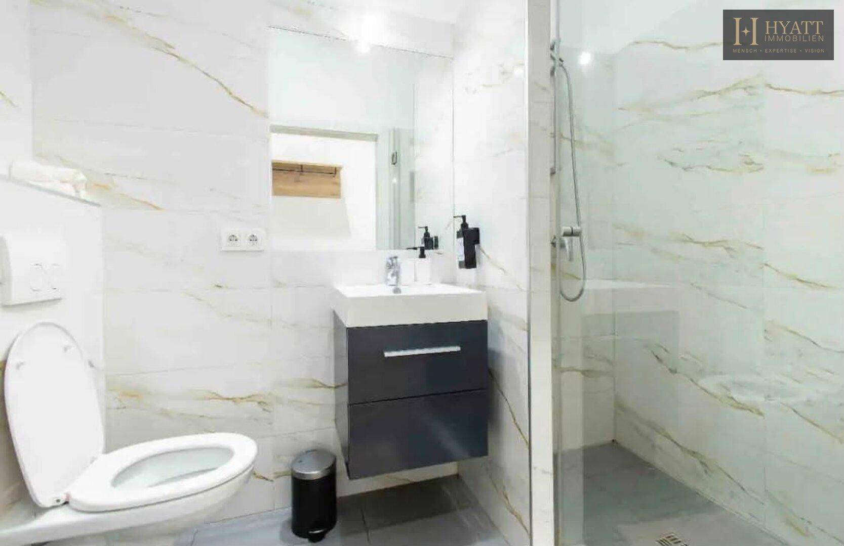 Modernes Badezimmer mit Marmorfliesen, Duschkabine und schwebendem Waschtischunterschrank.