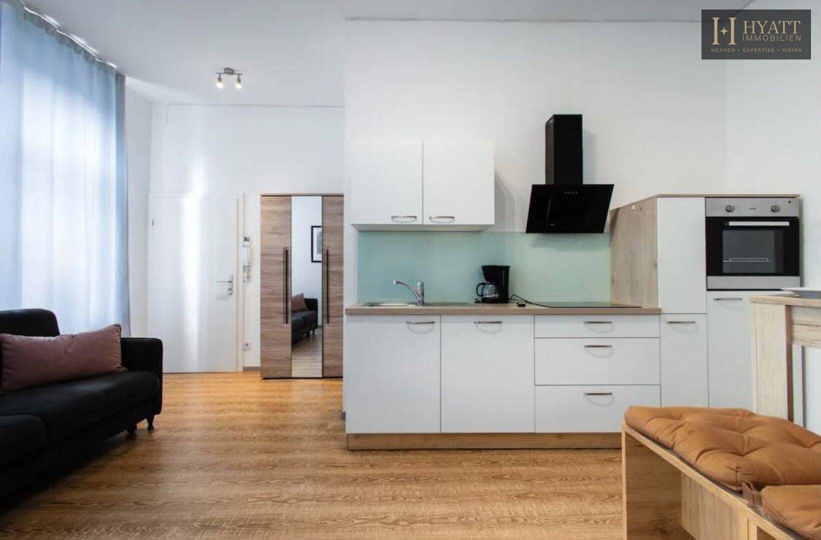 Offener Wohnbereich mit Küchenzeile, Sofa und Esstisch, ideal für kompaktes Wohnen.