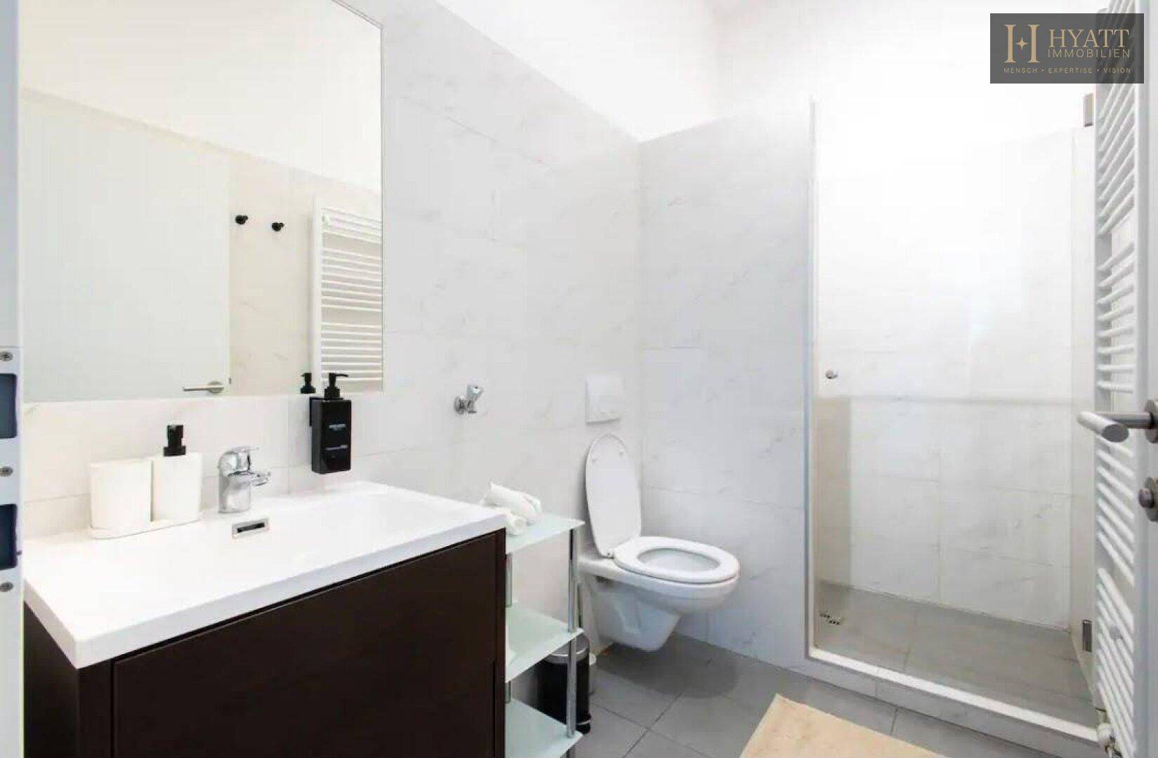 Modernes Badezimmer mit Duschkabine, wandhängendem WC und Handtuchheizkörper.