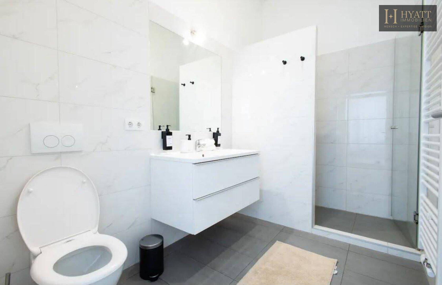 Modernes Badezimmer mit schwebendem Waschtisch, Duschkabine und wandhängendem WC.