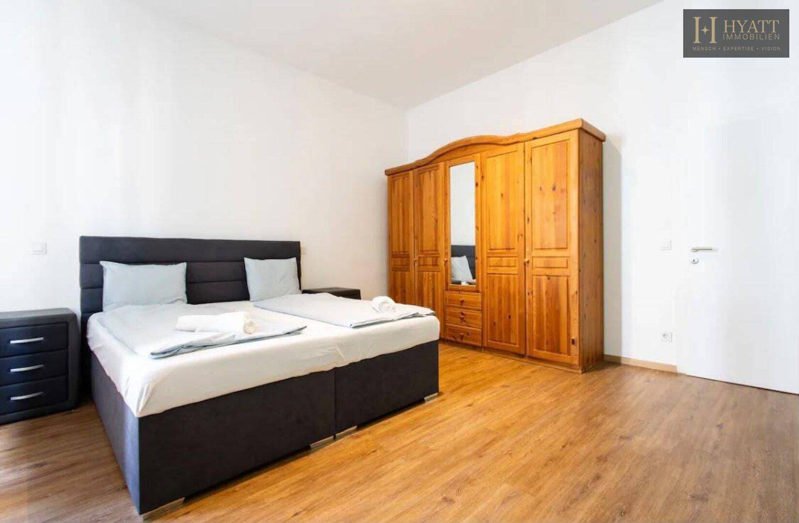 Gemütliches Schlafzimmer mit Doppelbett und großem Holzschrank, bietet viel Stauraum und ist hell.