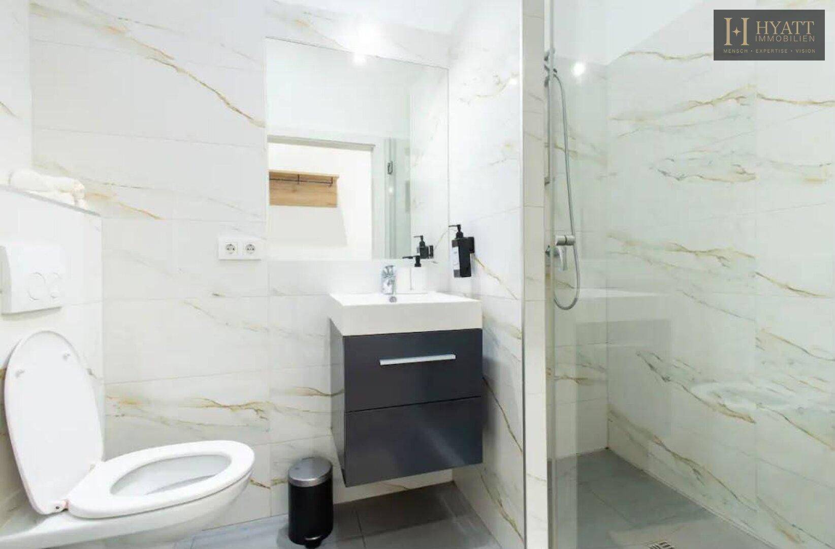 Modernes Badezimmer mit begehbarer Dusche, Hänge-WC und eleganten Marmorfliesen, sehr gepflegt.