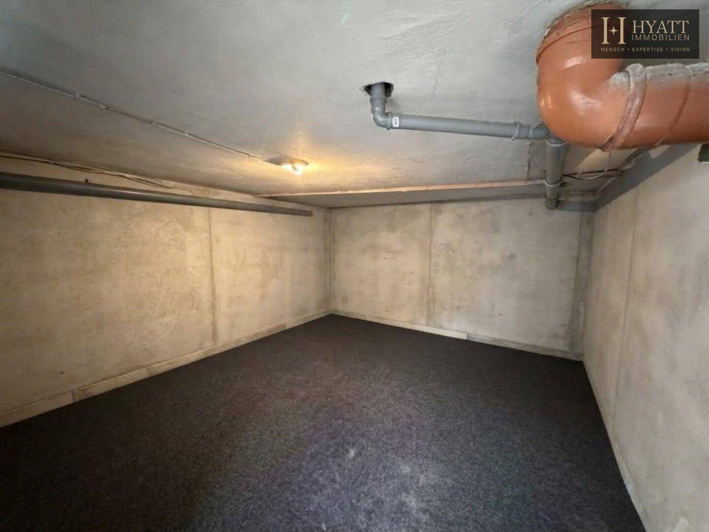 Unfertiger Kellerraum mit Betonwänden und Teppichboden, ideal als Lagerfläche.