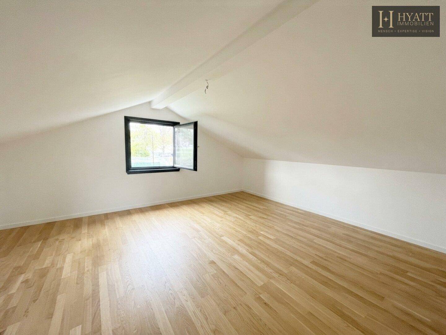 Helles Dachzimmer mit Holzboden und schrägen Wänden, ideal als Schlaf- oder Arbeitsbereich.