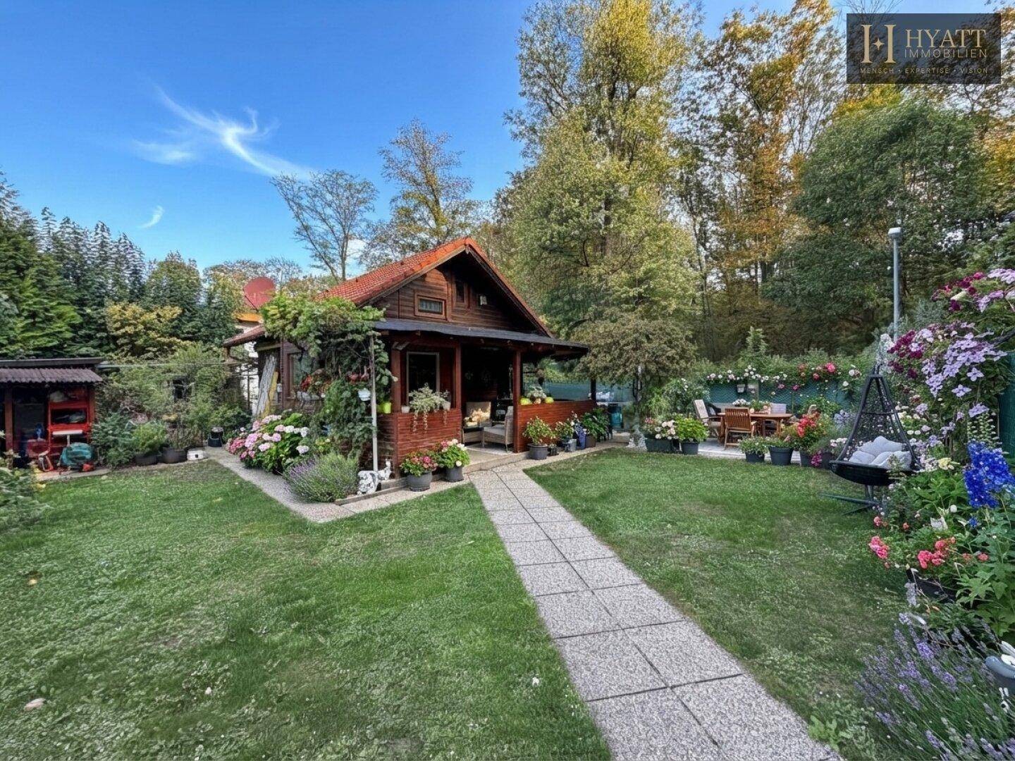Charmantes Holzhaus mit weitläufigem Garten und gemütlicher Sitzecke im Freien.