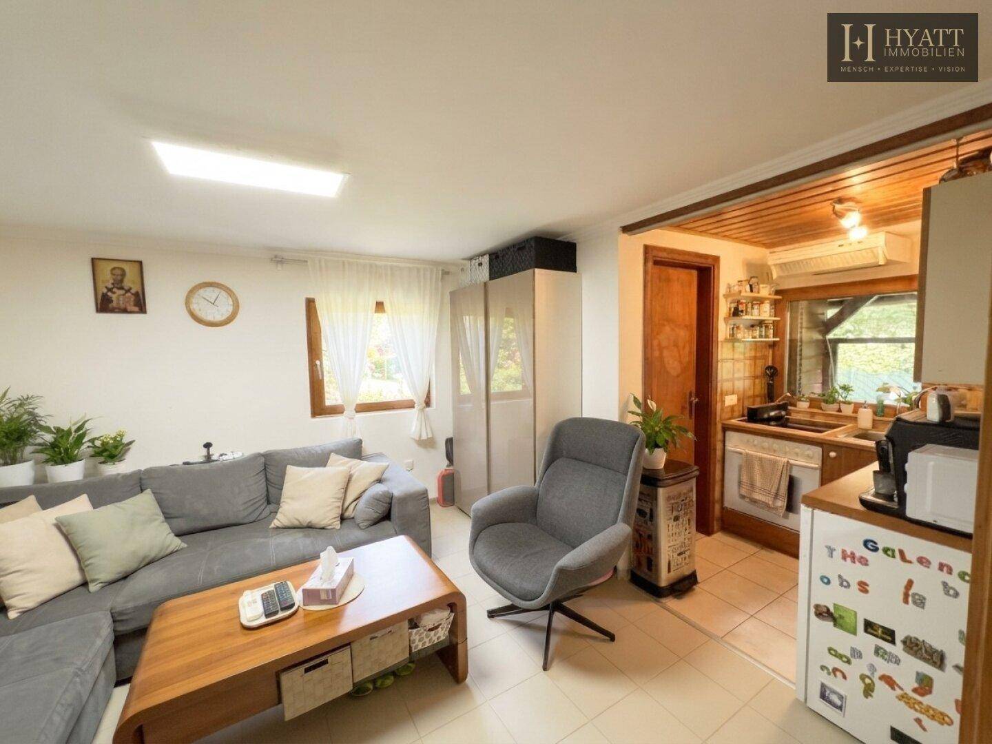 Heller Wohnbereich mit Sofa und integrierter Küchenzeile, ideal für offenes Wohnen.