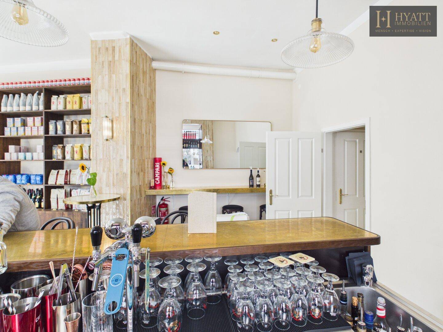 Detailansicht der Bar eines Cafés mit Gläsern, Zapfanlage und einem Spiegel an der Wand.