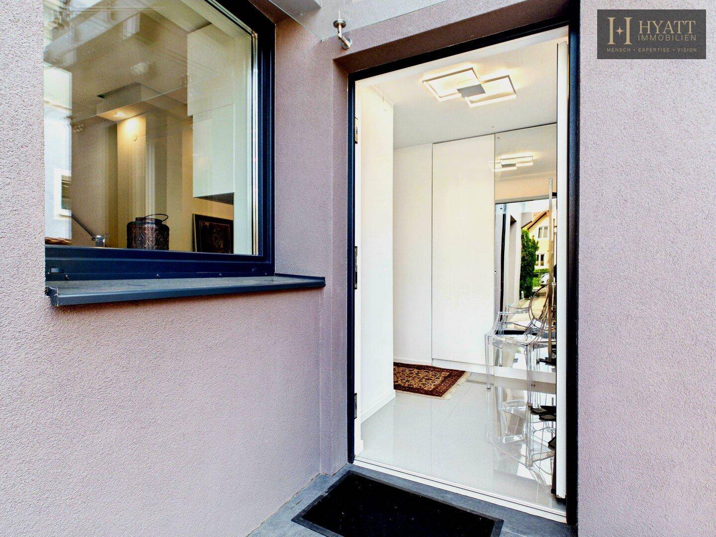 Heller Eingangsbereich mit modernen Fliesen, Spiegelschrank und Blick ins Innere des Hauses.
