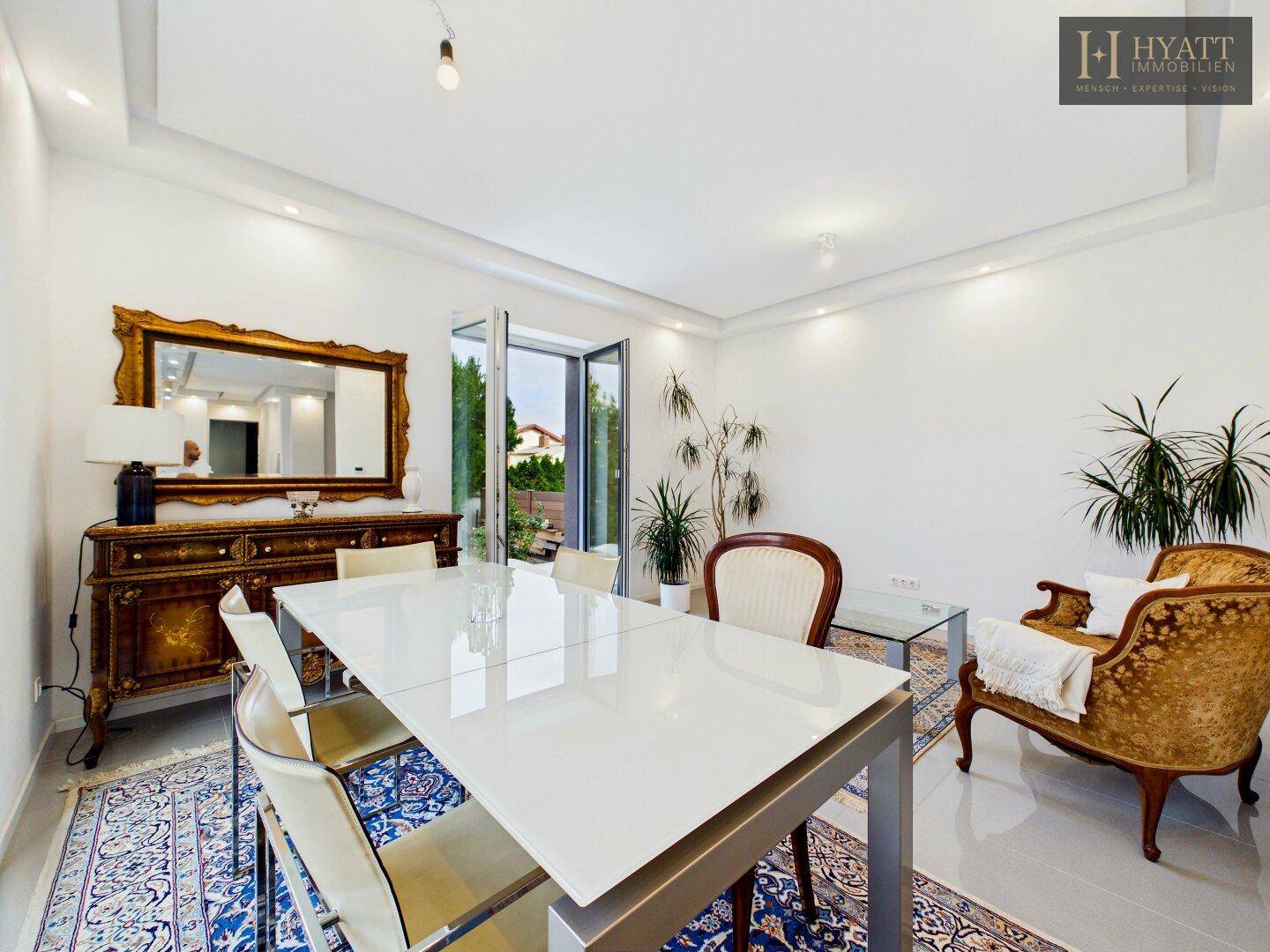 Eleganter Essbereich mit großem Esstisch, klassischem Sideboard und Zugang zur Terrasse.