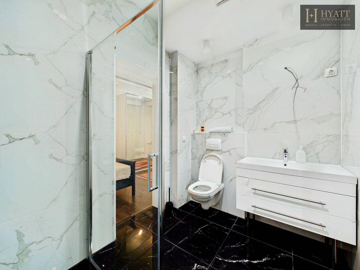 Modernes Badezimmer mit Marmorfliesen, schwarzem Boden und begehbarer Glasdusche.
