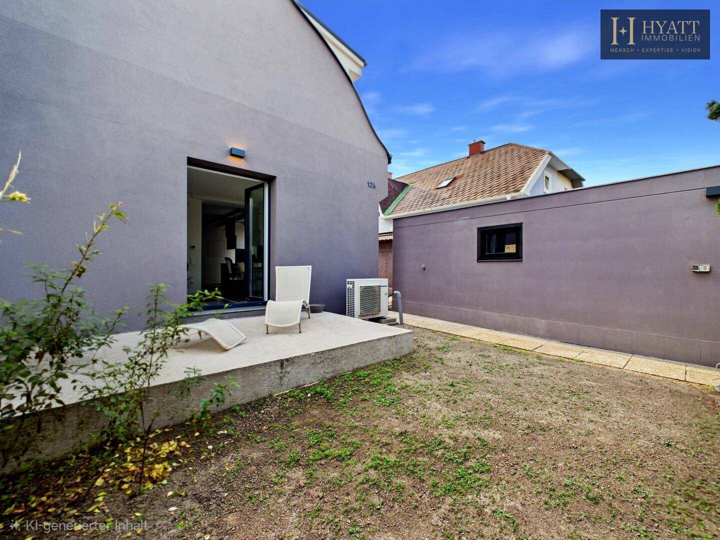 Gartenbereich hinter dem Haus mit kleiner Terrasse und Klimaanlage an der Fassade.