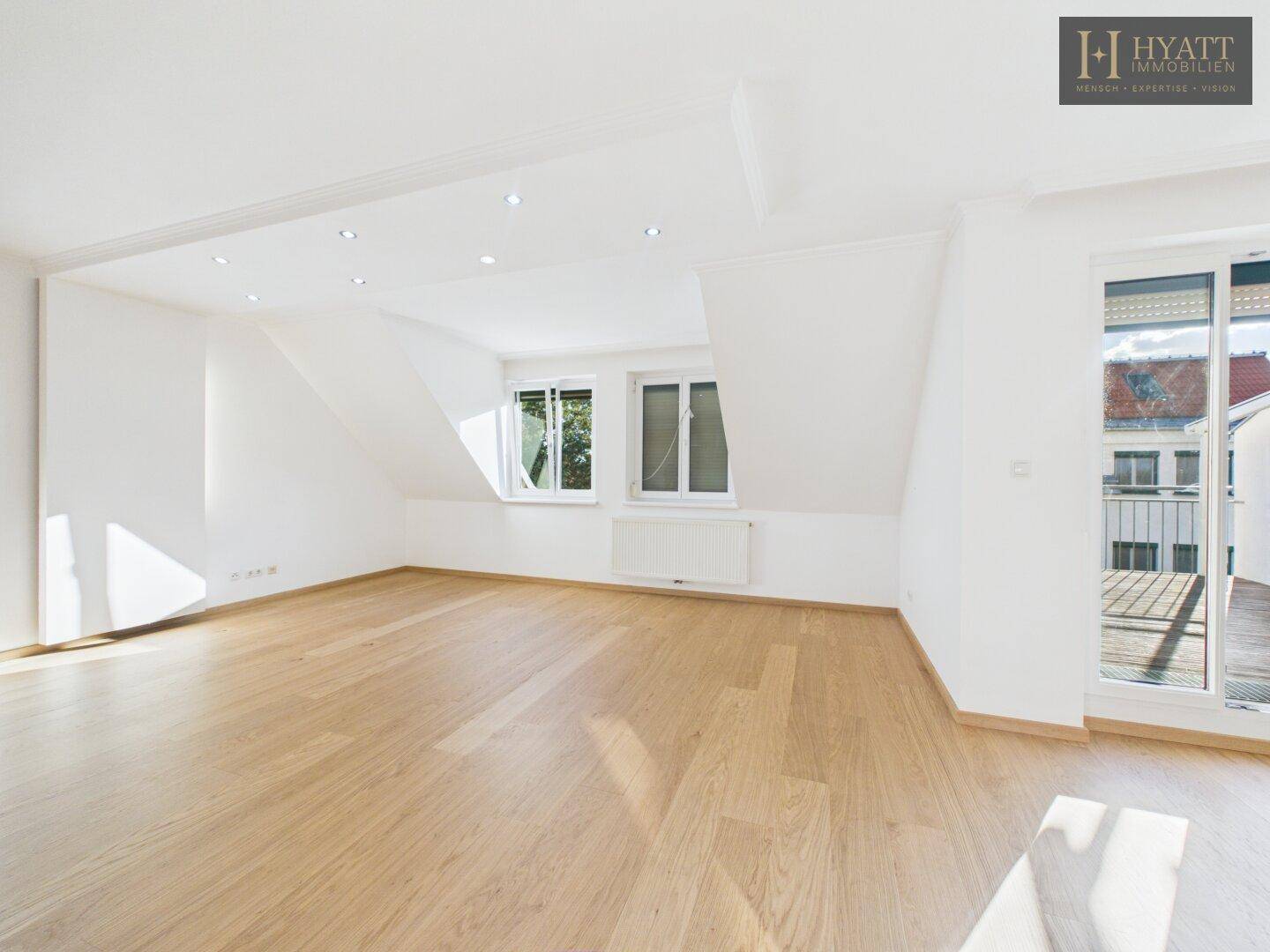 Geräumiges, helles Zimmer mit Holzboden, Dachschrägen und Zugang zum Balkon.
