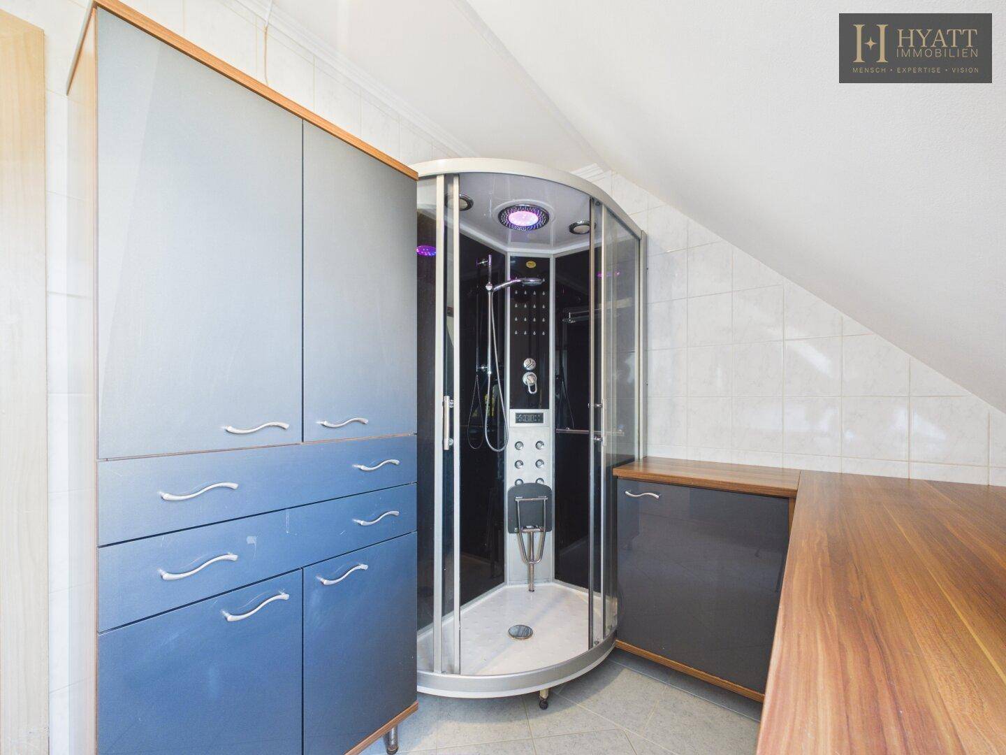 Modernes Badezimmer mit Duschkabine, Einbauschränken und Dachschräge.