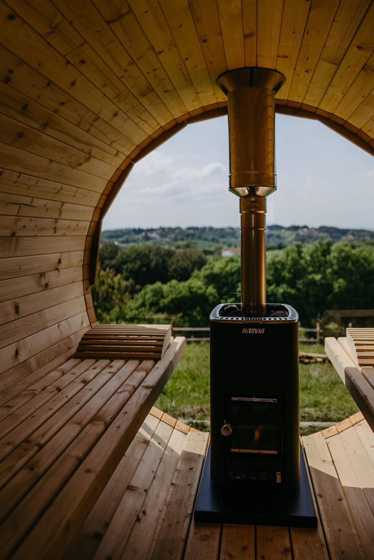Gemütliche Holzsauna mit Blick auf die grüne Landschaft durch die große runde Öffnung.