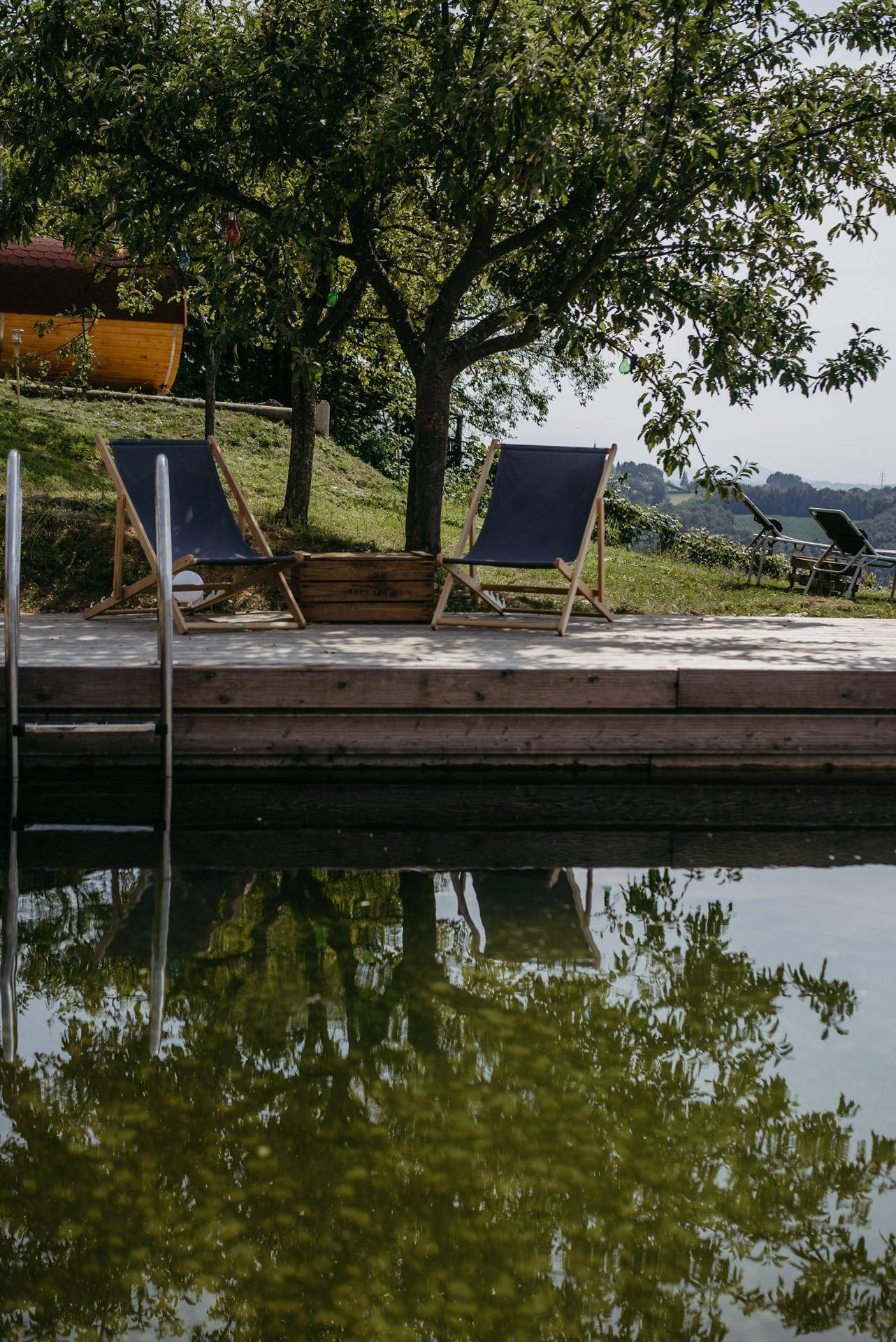 Entspannender Poolbereich im Garten mit Liegestühlen und viel Grün.