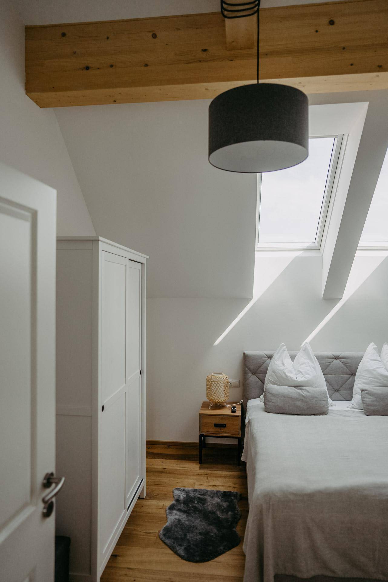 Helles Schlafzimmer mit Holzboden, Dachschrägen und einem Dachfenster für viel Tageslicht.