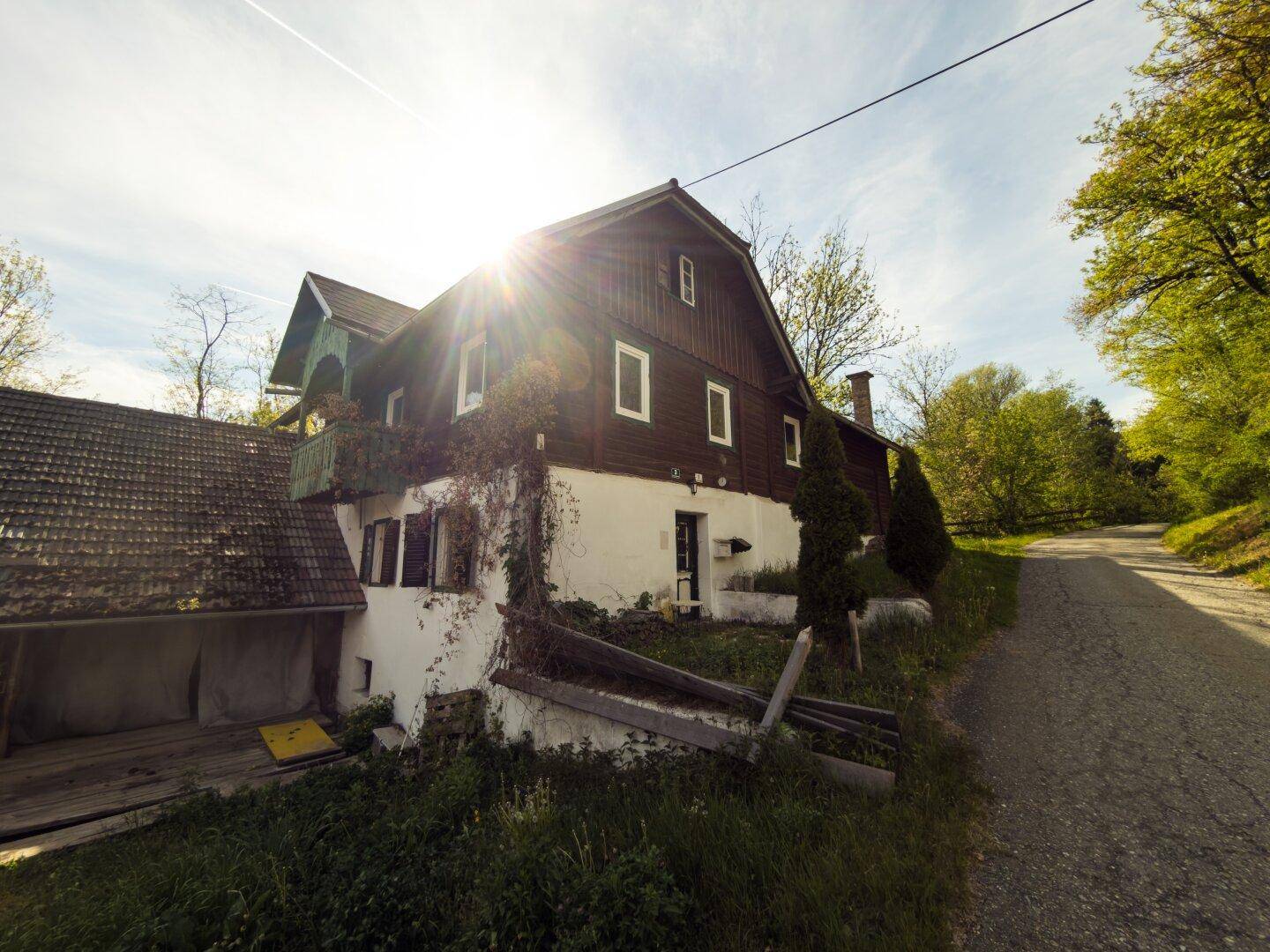 Ländliches Wohnhaus mit Holzfassade, kleinem Balkon und viel Grün in sonniger Lage.