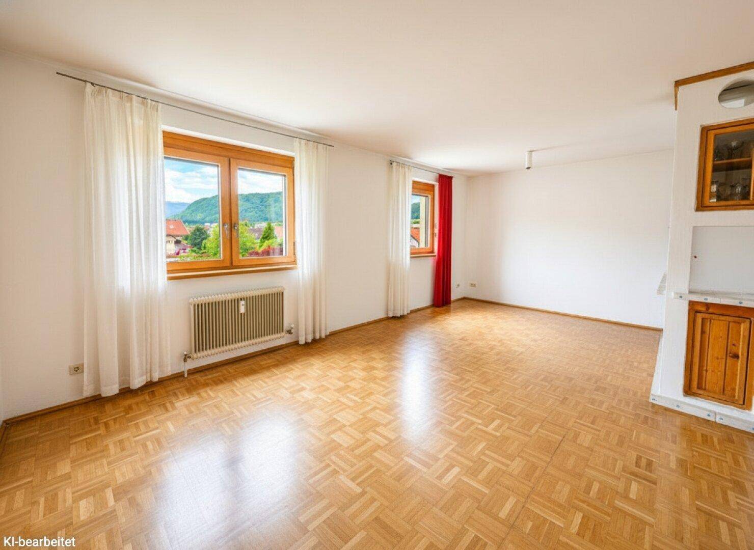 Geräumiges Wohnzimmer mit Parkettboden, hellen Wänden und Blick ins Grüne.