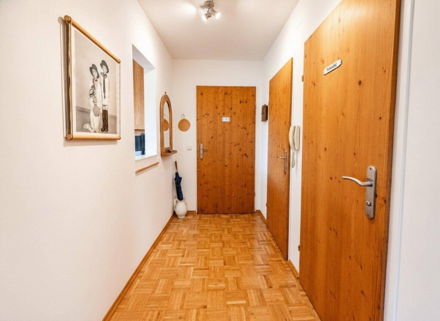 Heller Flur mit Parkettboden und Holztüren, der zu den verschiedenen Räumen führt.