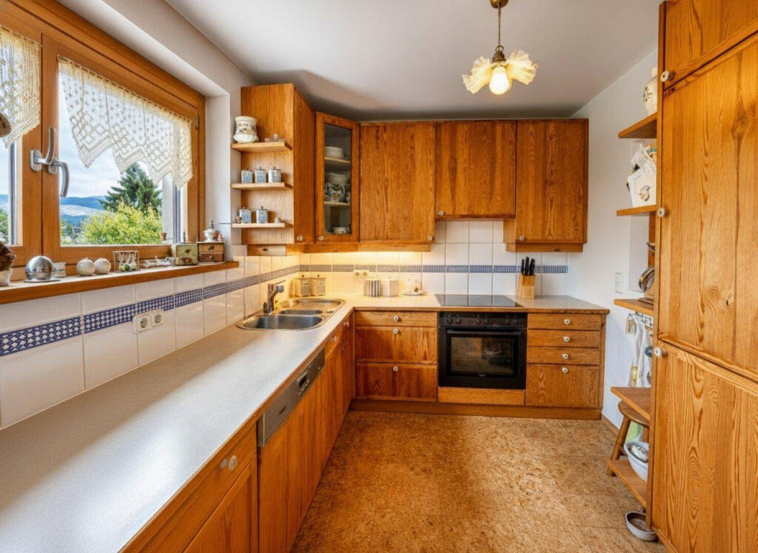 Funktionale Küche mit Holzschränken, Fliesenrückwand und Fenster mit Bergblick.