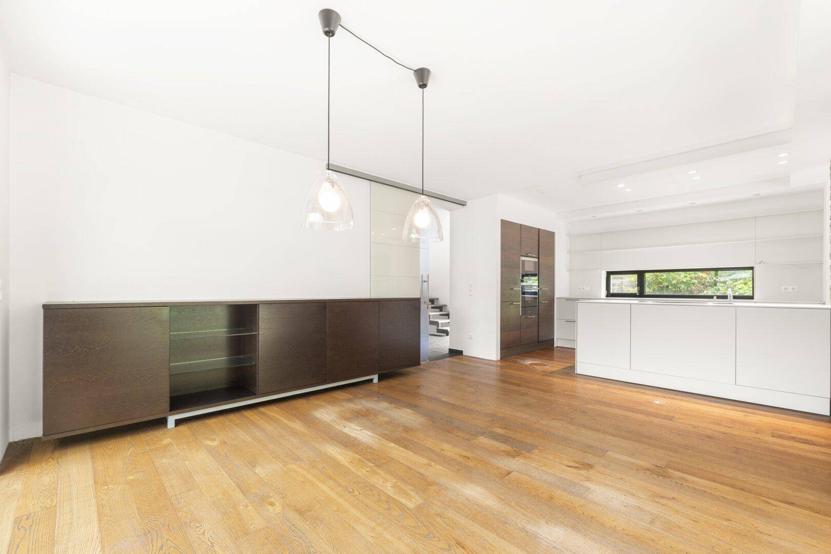 Offener Wohnbereich mit Holzboden und Blick auf die moderne Küche.