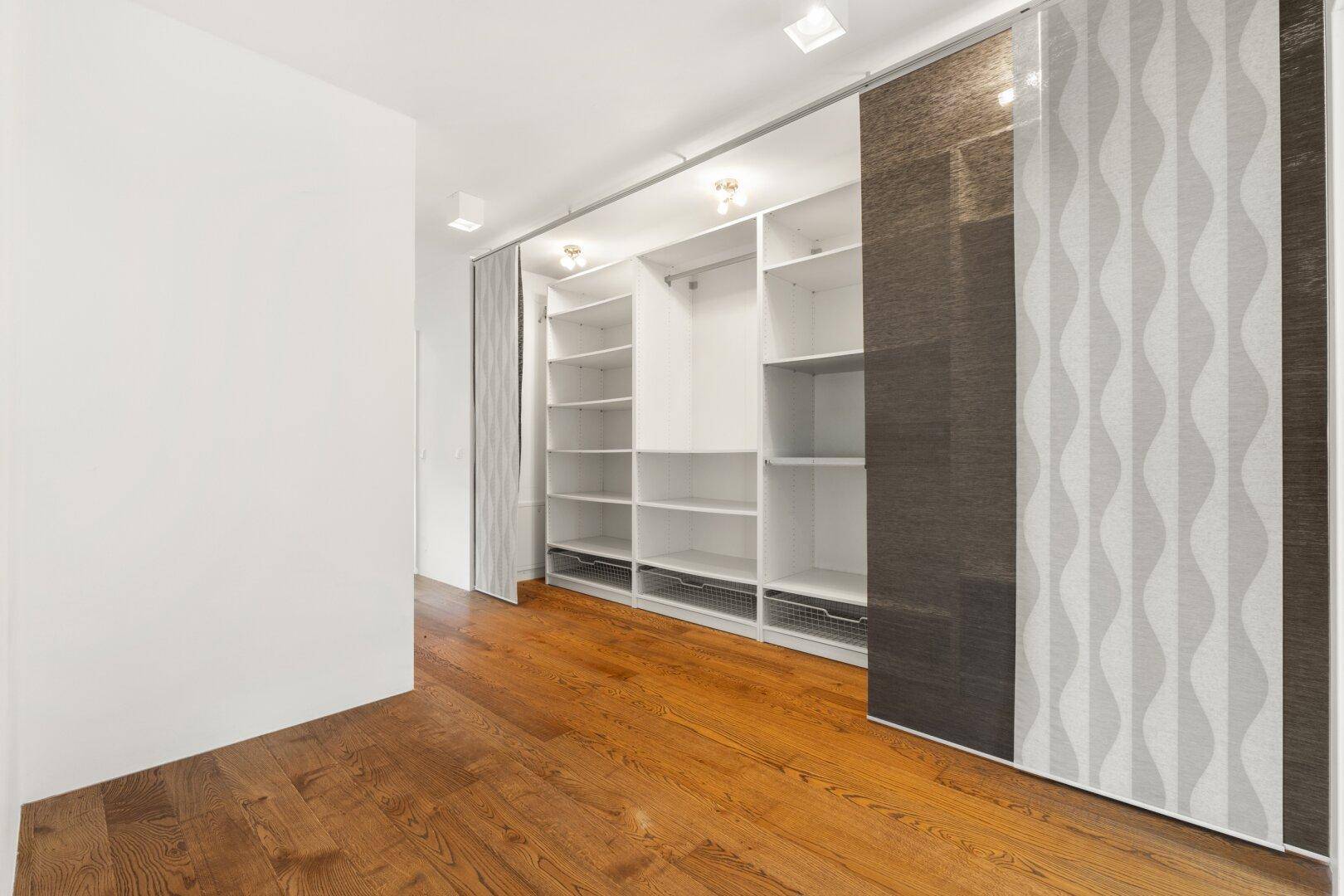 Praktischer begehbarer Kleiderschrank mit vielen Regalen und Stauraum.