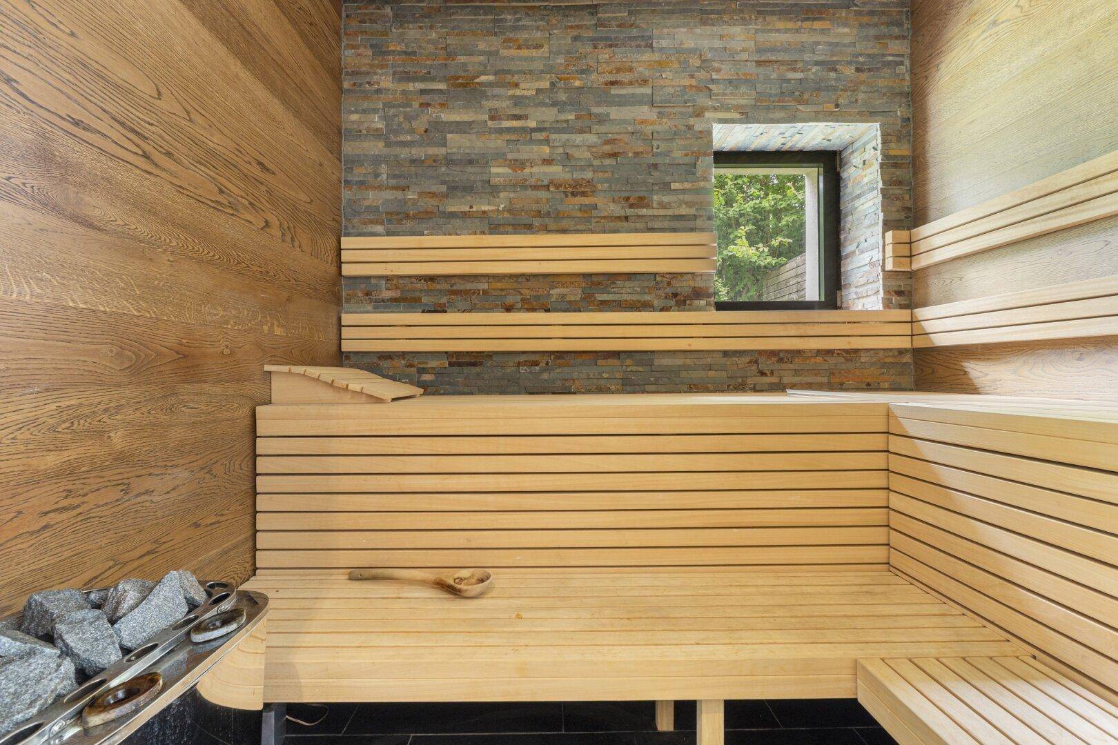 Gemütliche Sauna mit Holzbänken und Steinofen, perfekt für entspannende Momente.