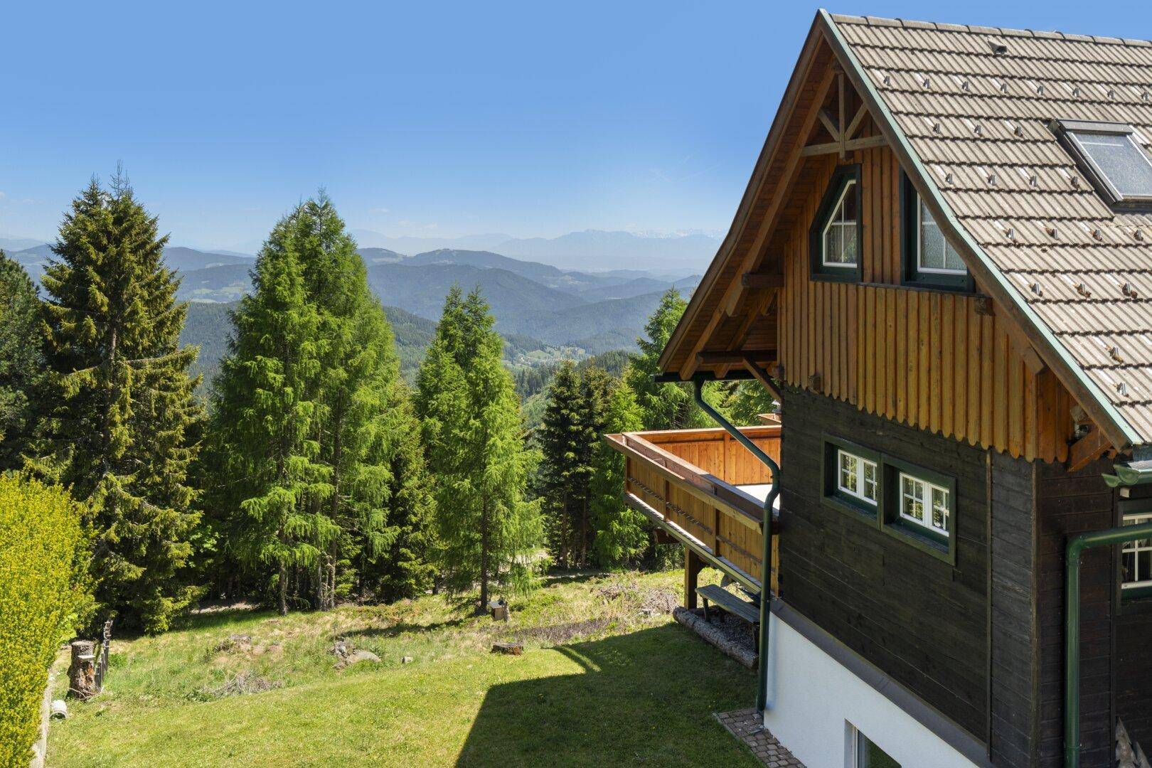 Charmantes Chalet mit Holzfassade und Satteldach, eingebettet in eine malerische Berglandschaft mit vielen Bäumen.
