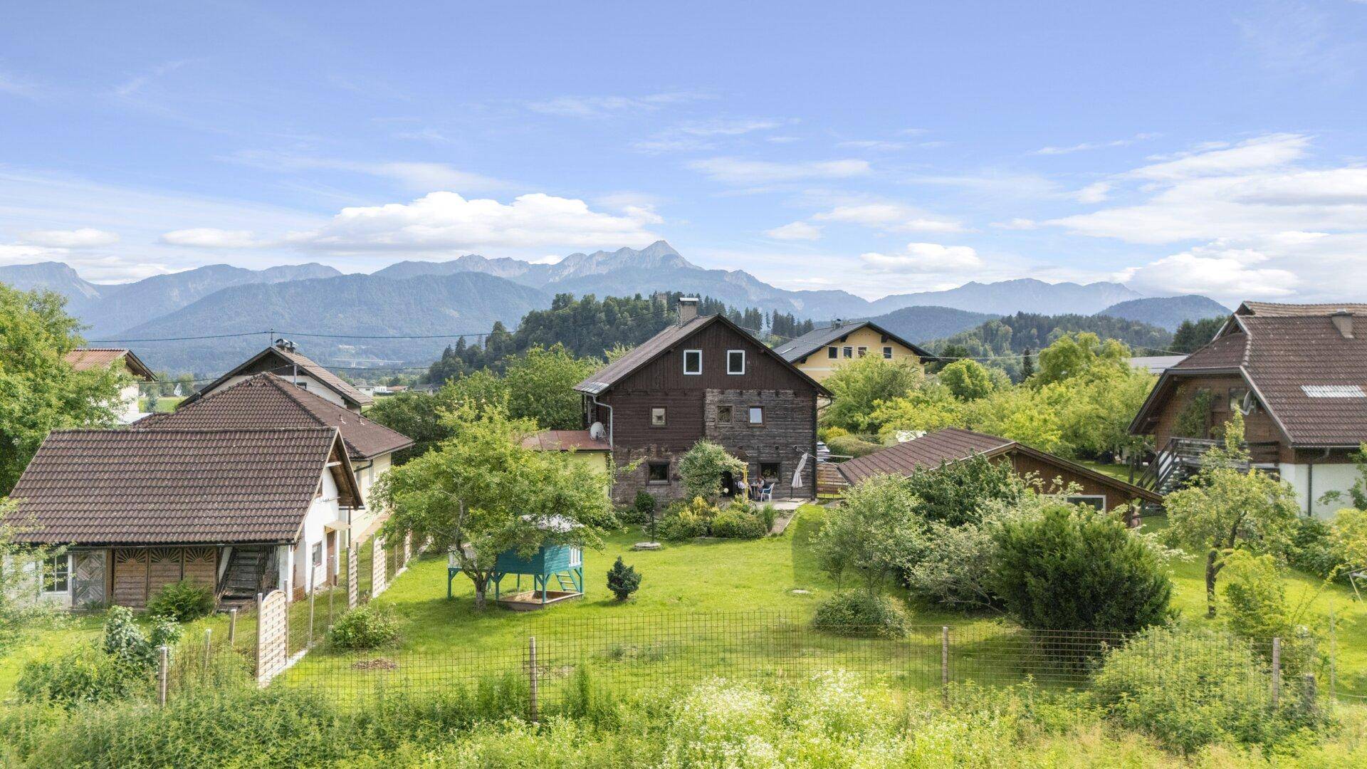 Ländliche Ansicht des Anwesens mit umliegenden Häusern und Bergen im Hintergrund.