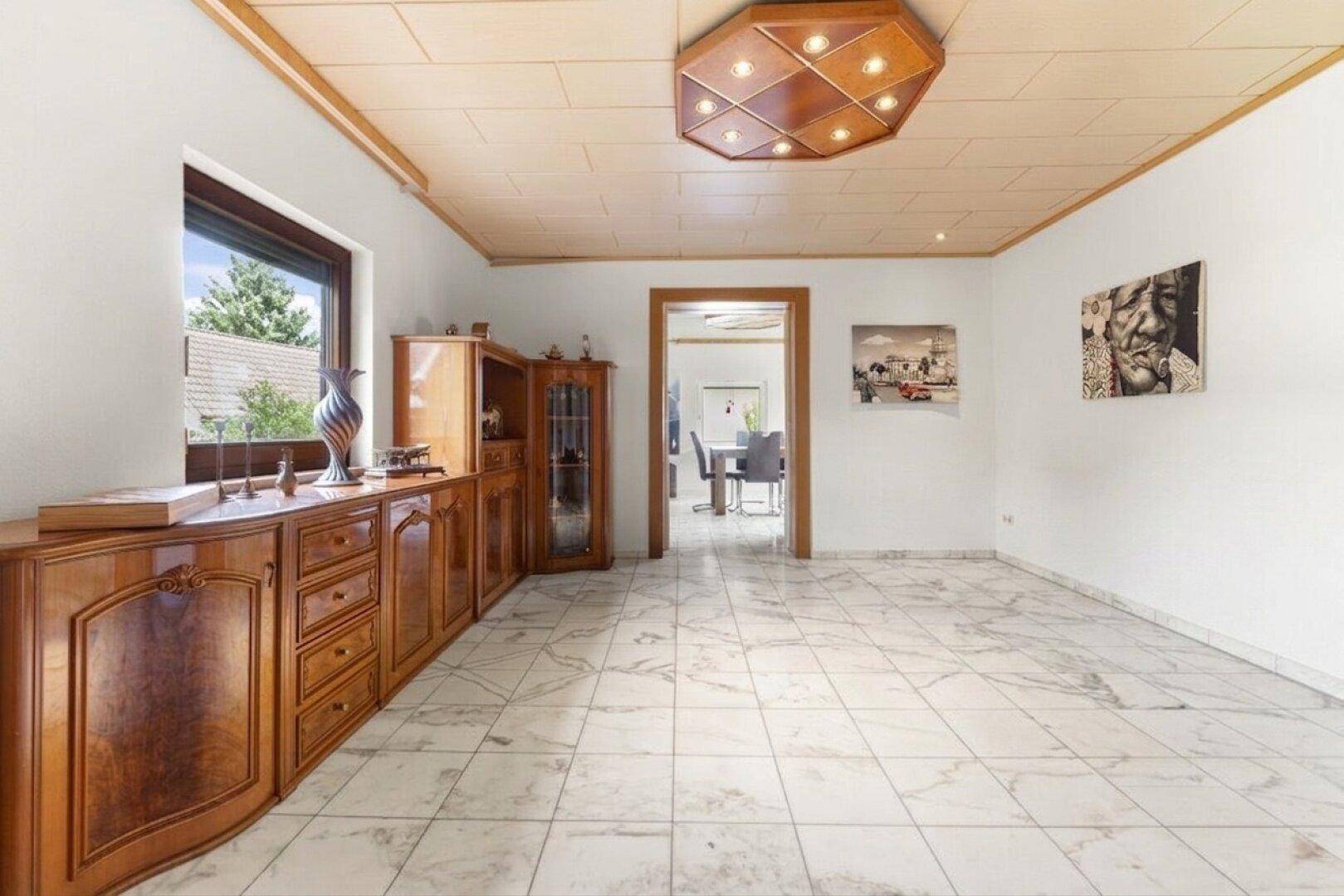 Geräumiges Wohnzimmer mit Marmorfliesenboden, Holzdecke und traditionellen Holzmöbeln.