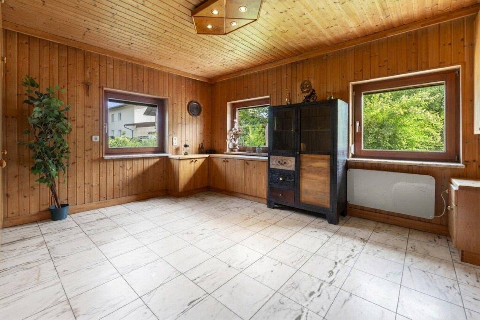 Rustikaler Raum mit Holzvertäfelung an Wänden und Decke sowie hellem Fliesenboden.