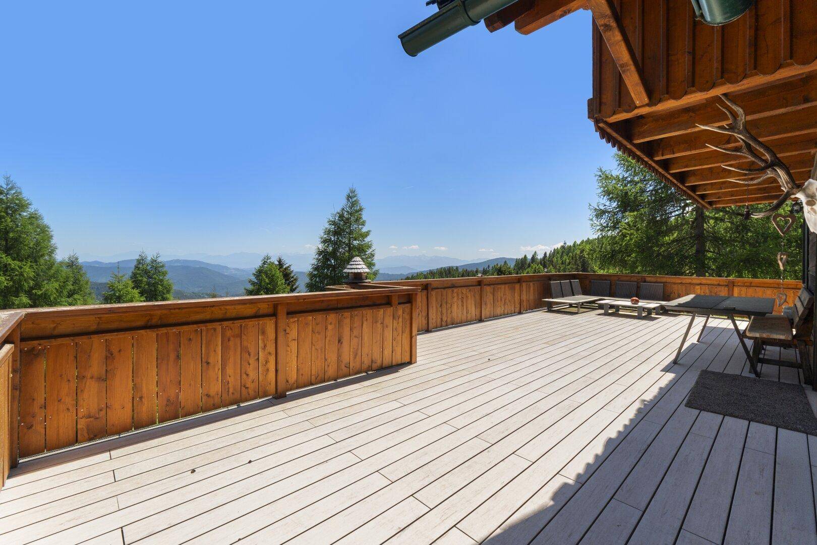 Sonnige Holzterrasse mit Panoramablick auf die Berge und umliegende Natur.