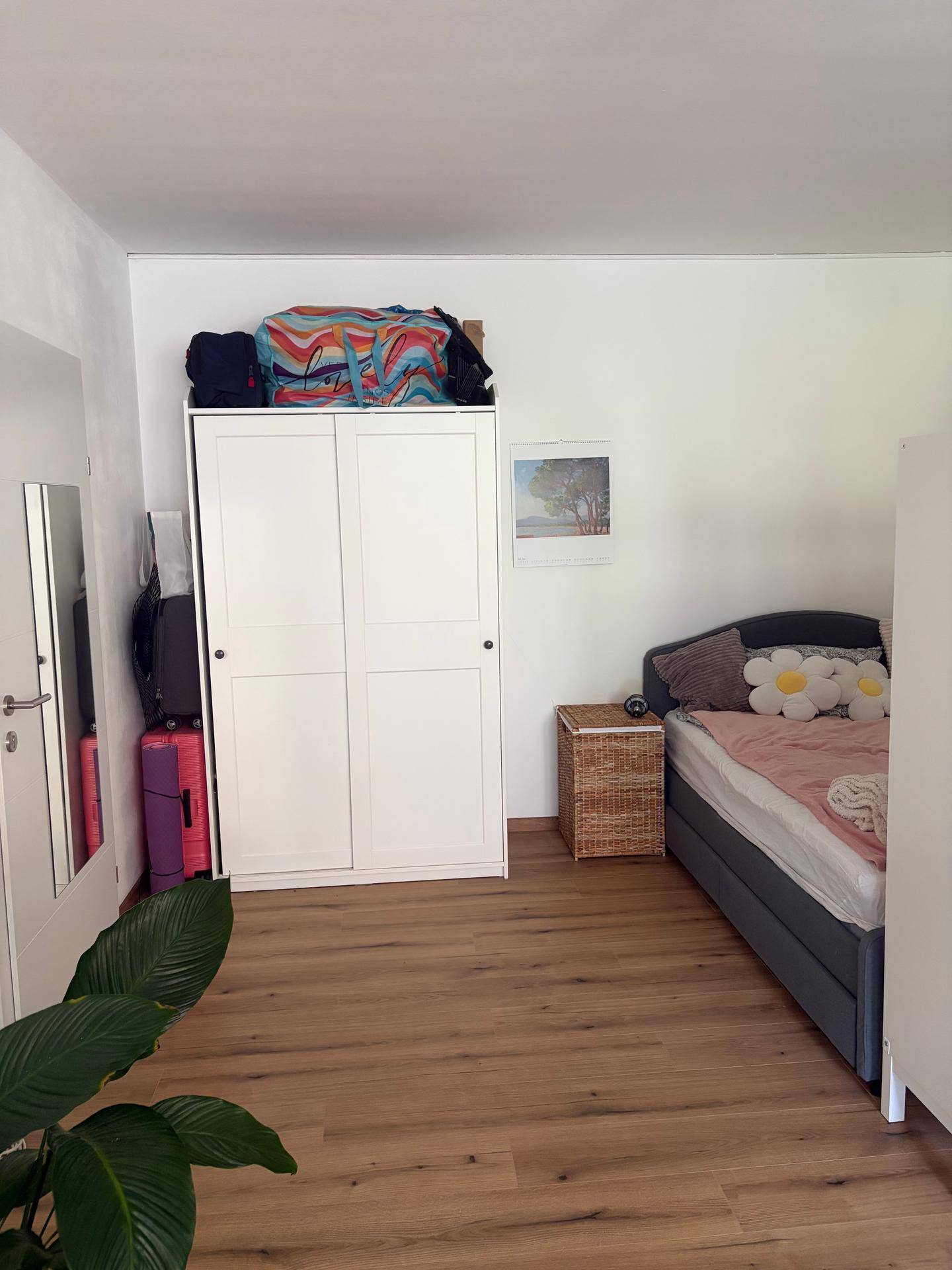 Gemütliches Schlafzimmer mit Einzelbett, weißem Kleiderschrank und hellem Holzboden.