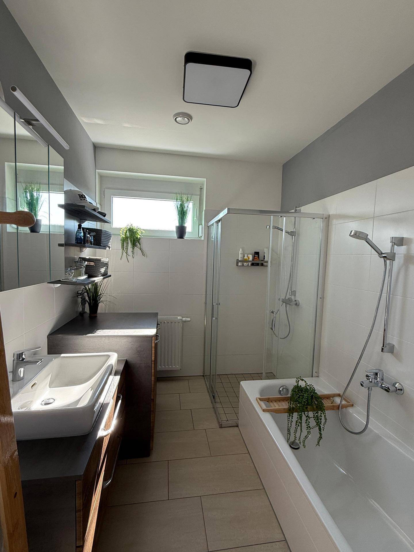Modernes Badezimmer mit Badewanne, separater Dusche, Fenster und Einzelwaschbecken mit Unterschrank.