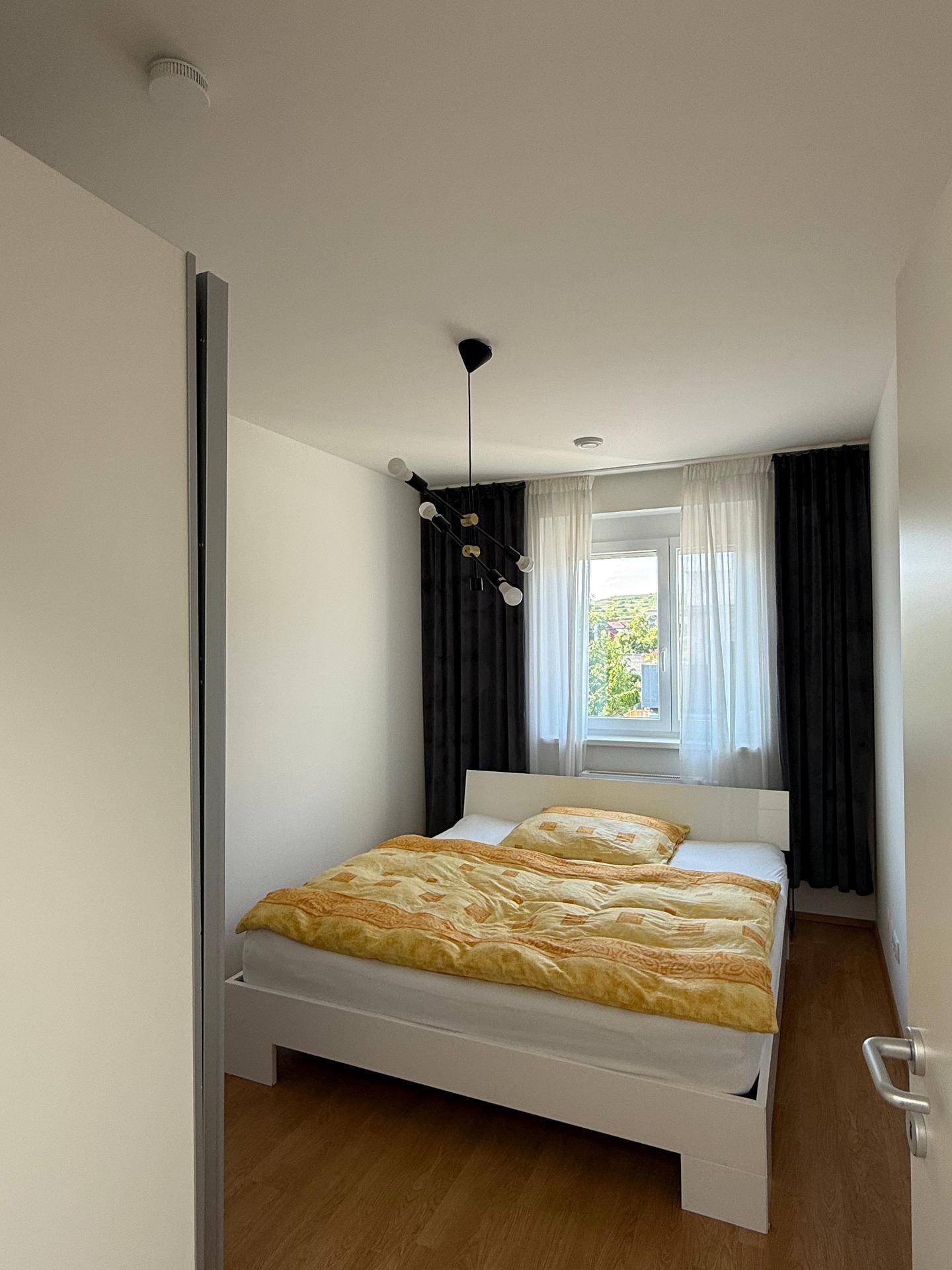 Helles Schlafzimmer mit weißem Bett, gelber Bettwäsche und modernem Deckenlicht, einladend gestaltet.