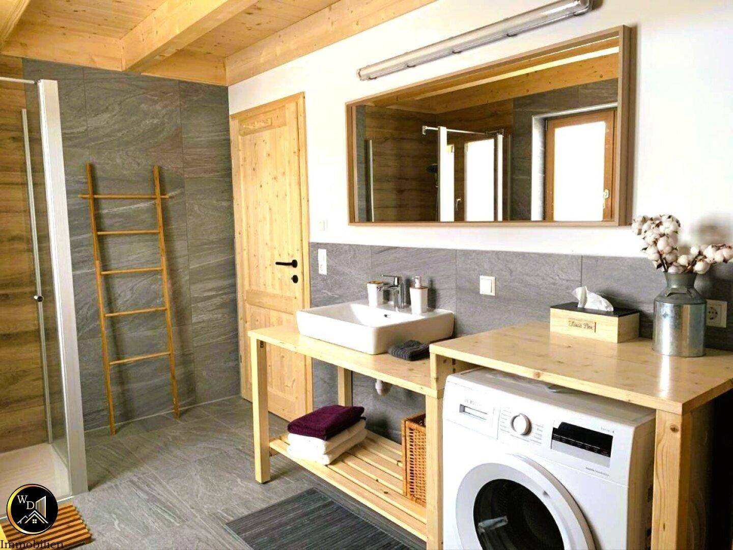 Helles Badezimmer mit Einzelwaschbecken, Waschmaschine und großem Spiegel.