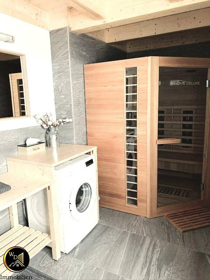Badezimmer mit integrierter Sauna, Waschmaschine und modernen Fliesen.