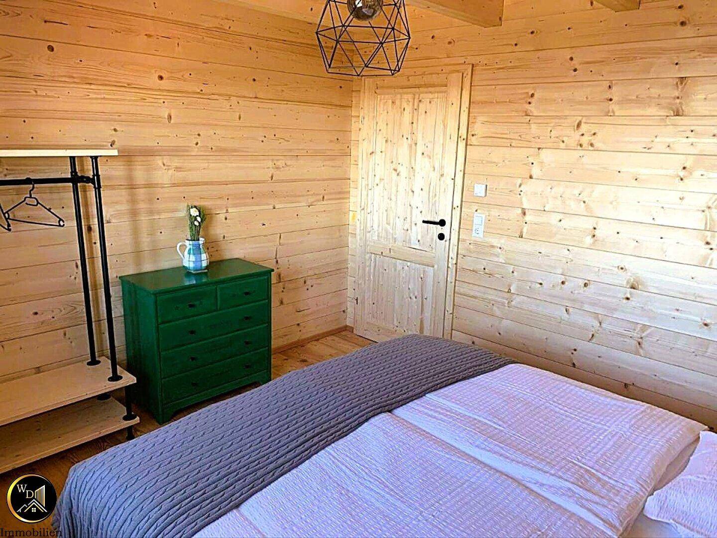 Schlafzimmer mit Holzwänden, Doppelbett und moderner Beleuchtung.