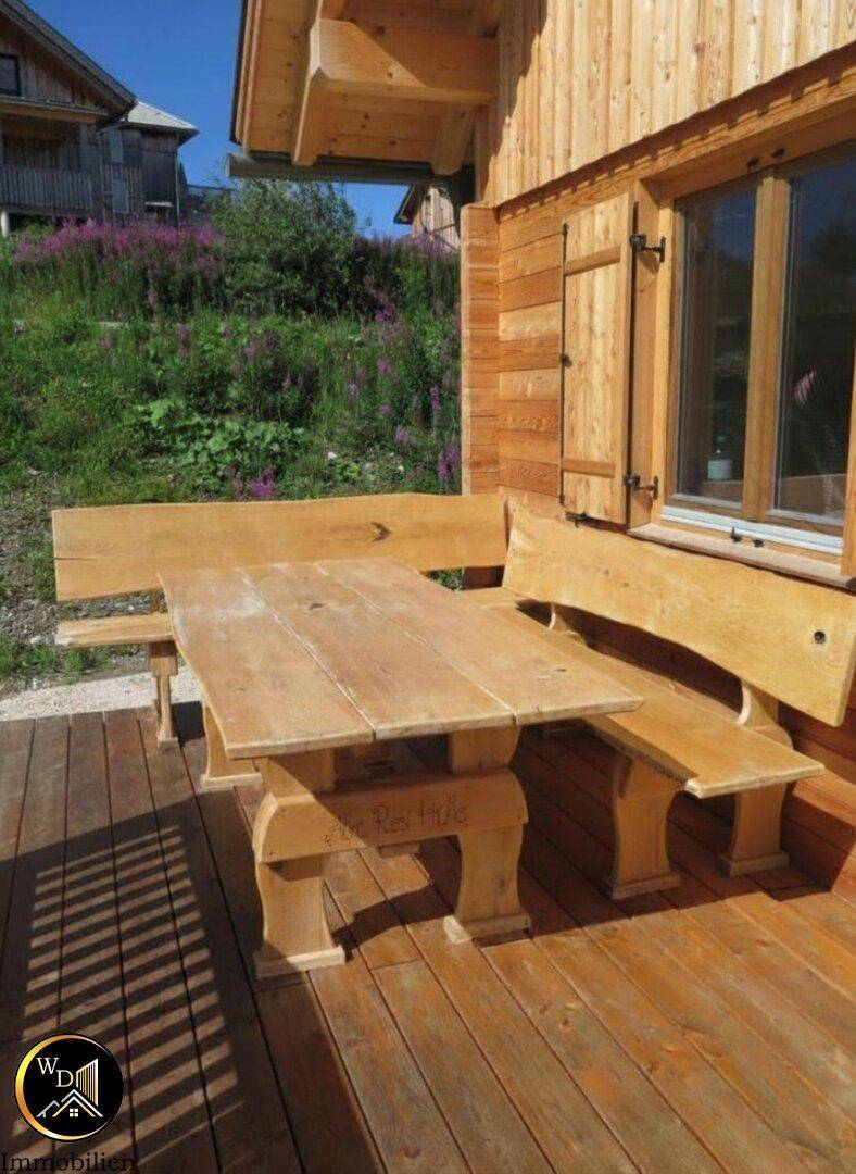Gemütlicher Essbereich im Freien auf der Holzterrasse mit rustikalen Holzmöbeln.