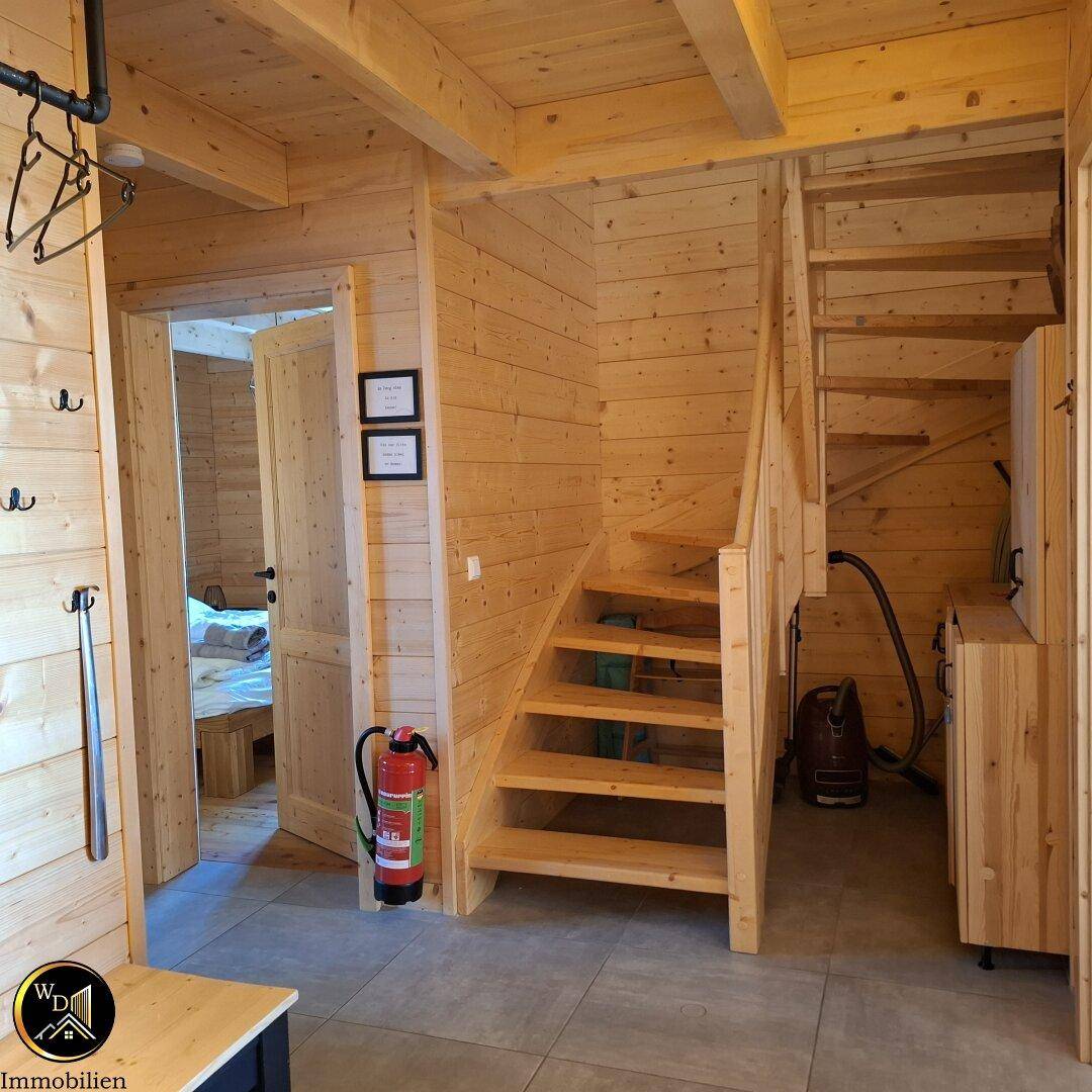 Heller Eingangsbereich mit Holzvertäfelung, Treppe zum Obergeschoss und Fliesenboden.