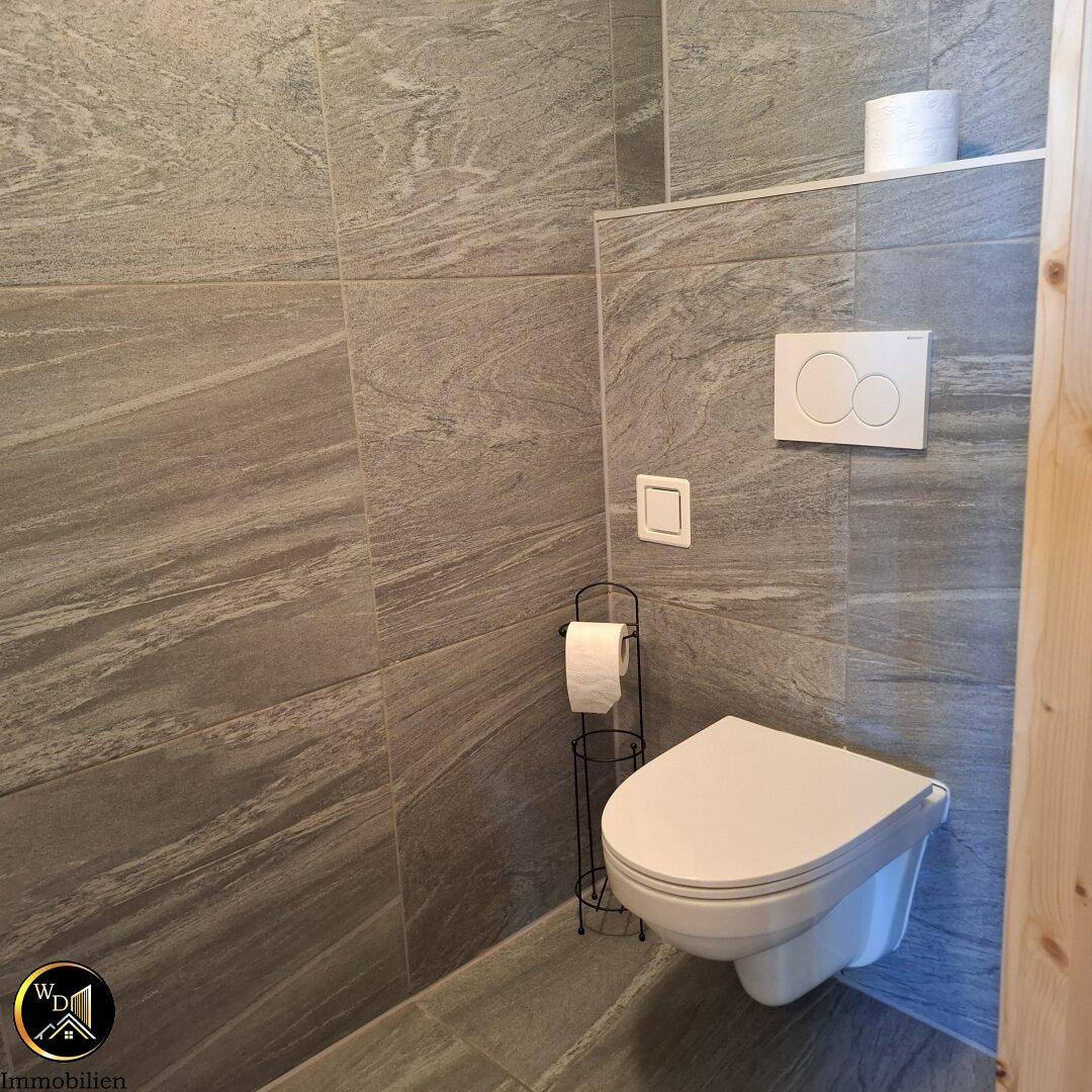 Modernes Gäste-WC mit Wand-WC und grauen Fliesen.