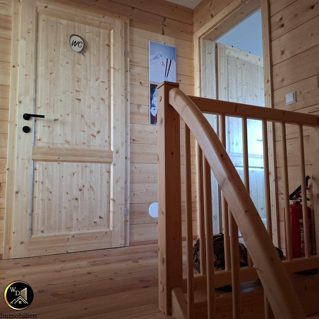 Flur mit Holzvertäfelung, Treppe und Zugang zum Gäste-WC.