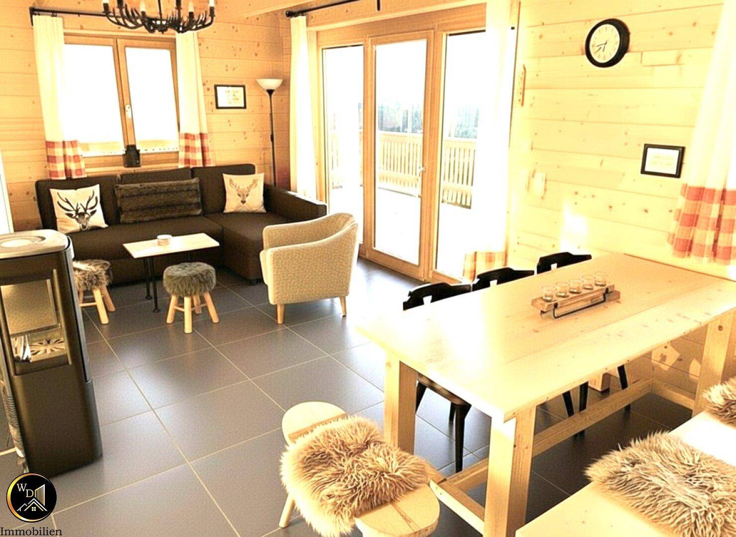 Heller Wohn-Essbereich mit Zugang zur Terrasse, Kaminofen und Holzwänden.