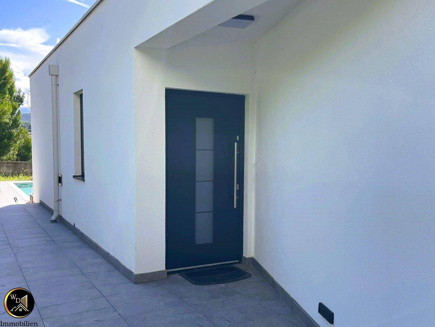 Moderner Hauseingang mit dunkler Tür und seitlichem Fenster, umgeben von weißer Fassade.