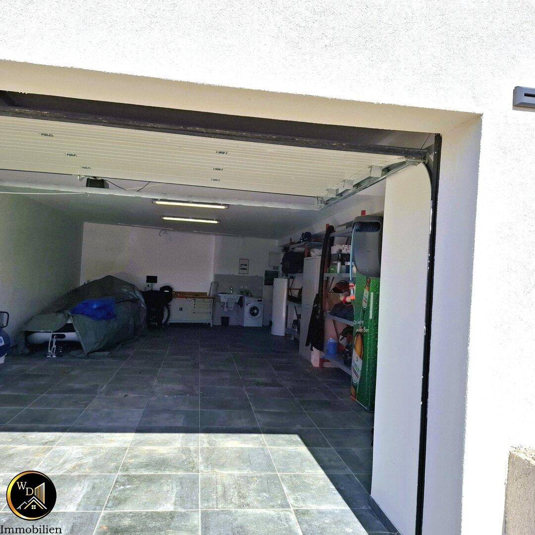 Geräumige Garage mit Fliesenboden, Stauraum und Waschmaschine.